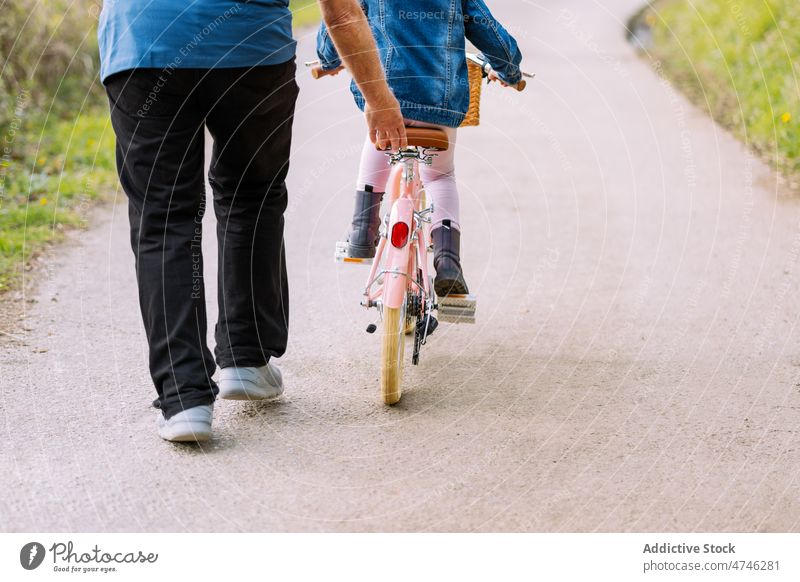 Anonymer Großvater unterrichtet Mädchen beim Fahrradfahren auf dem Lande Hobby Freizeit Kindheit Zeit verbringen Mitfahrgelegenheit Landschaft Hilfsbereitschaft
