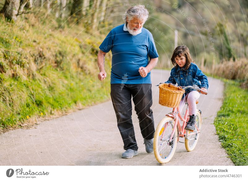 Großvater läuft mit Enkelin auf dem Fahrrad Mädchen Hobby Freizeit Kindheit Zeit verbringen Mitfahrgelegenheit Landschaft laufen Energie Aktion freie Zeit Mann