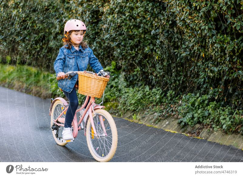 Mädchen fährt Fahrrad im Park Kind Hobby Freizeit Zeitvertreib Kindheit Verkehr Schutzhelm Weg Fokus Korb Aktivität Sommer Baum Sicherheit Konzentration