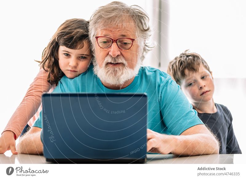 Großvater surft mit Kindern auf dem Laptop Browsen Video online Internet unterhalten Zeitvertreib Freizeit heimwärts Junge Mädchen Geschwisterkind Netbook