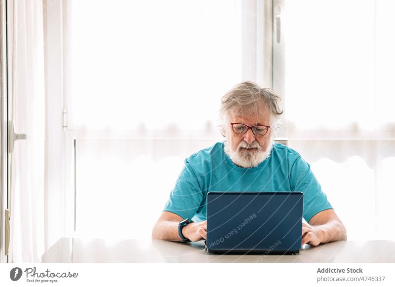 Älterer Mann mit Laptop zu Hause Browsen freie Zeit Wochenende benutzend Apparatur Gerät Internet online Fokus Netbook achtsam heimwärts zuschauend männlich