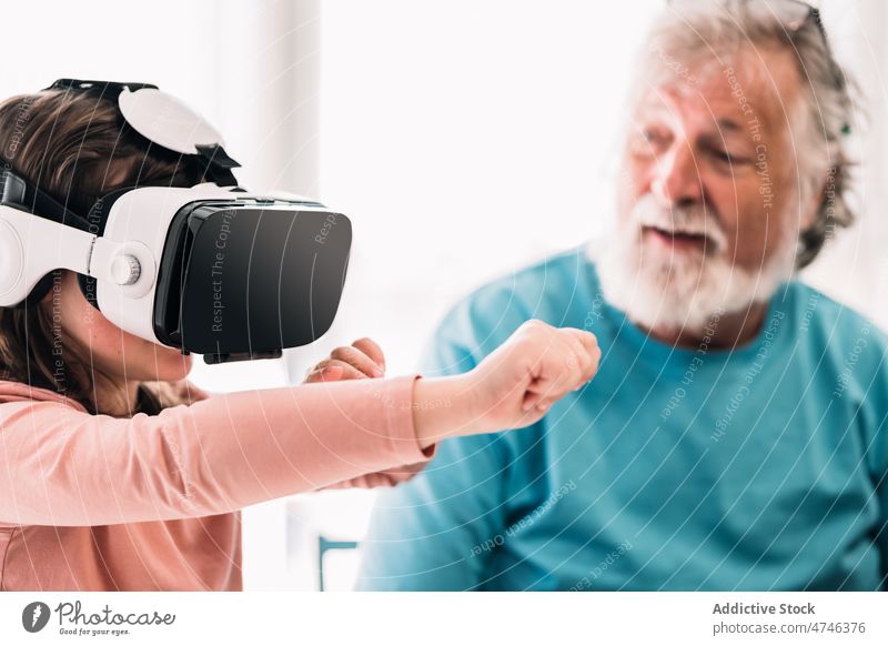 Mädchen in VR-Headset bei Großvater Schutzbrille erkunden Cyberspace futuristisch Virtuelle Realität eintauchen Simulator modern älter Rentnerin männlich