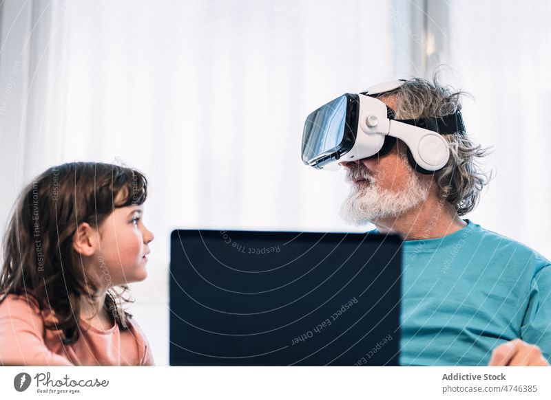 Großvater mit VR-Headset spielt Videospiel in der Nähe eines Mädchens erkunden Cyberspace futuristisch eintauchen Virtuelle Realität Laptop Netbook Browsen