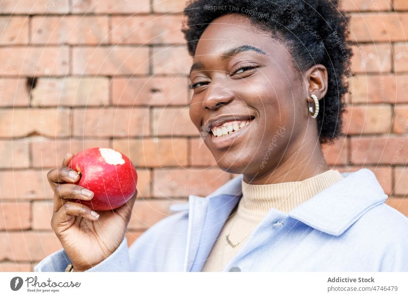 Schwarze Frau isst Apfel auf der Straße Frucht gesunde Ernährung essen Glück Großstadt Vitamin Lächeln Laufsteg Lebensmittel Stil Vorschein feminin urban