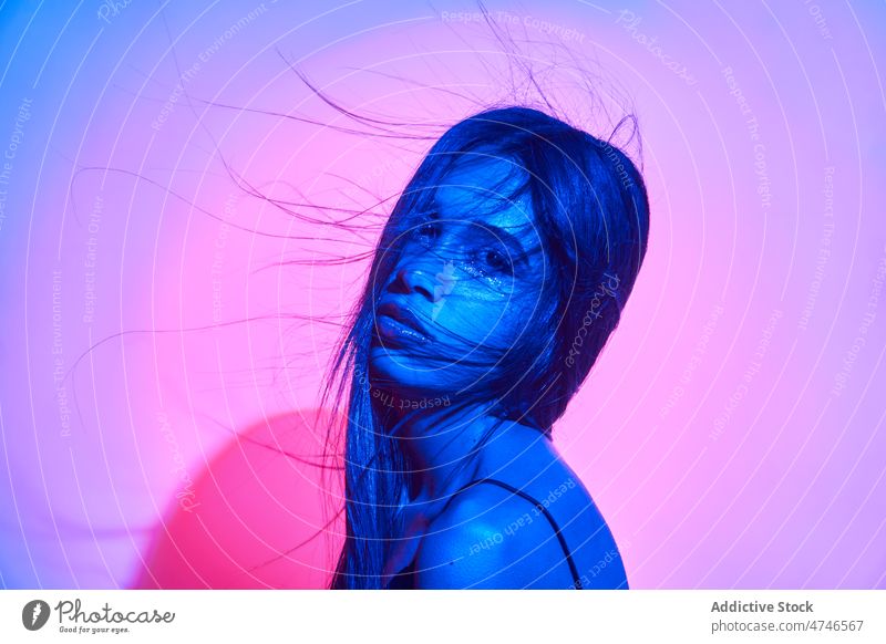 Verführerische Frau mit fliegendem unordentlichem Haar im Studio selbstbewusst Stil cool provokant Porträt Verlockung neonfarbig hell Starrer Blick