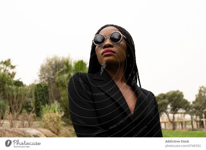 Stilvolle schwarze Frau auf der Straße Sonnenbrille trendy Großstadt feminin Mode Vorschein Outfit Afroamerikaner selbstbewusst Sommer Baum cool ernst Dame