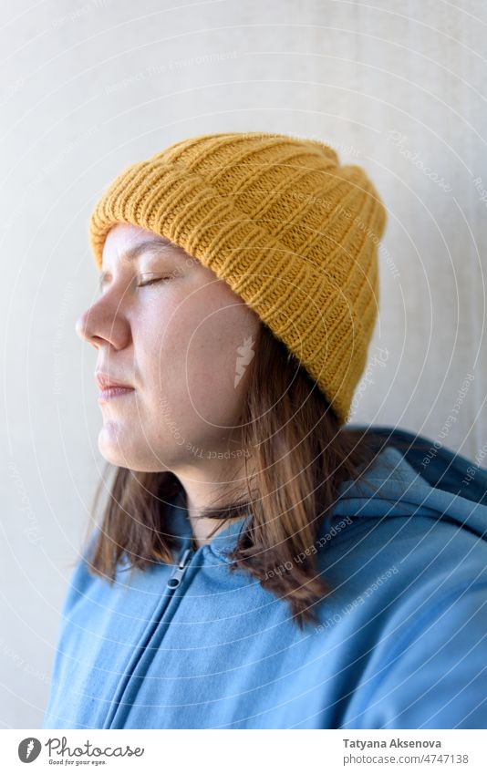 Frau mit gelbem Hut und blauem Sweatshirt Angst beunruhigt Sorge traurig gestrickt 30s tausendjährig Augen geschlossen Kaukasier Selfie authentisch