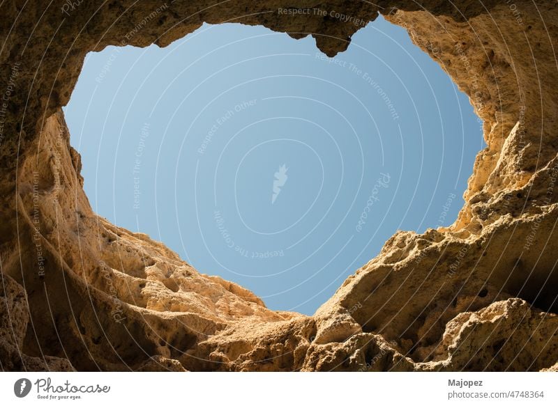 Steinhöhle mit einem herzförmigen Loch im Dach. Blauer Himmel vom Inneren der Höhle aus gesehen. Algarve, Portugal Natur wandern Park Bogen Sandstein Geologie