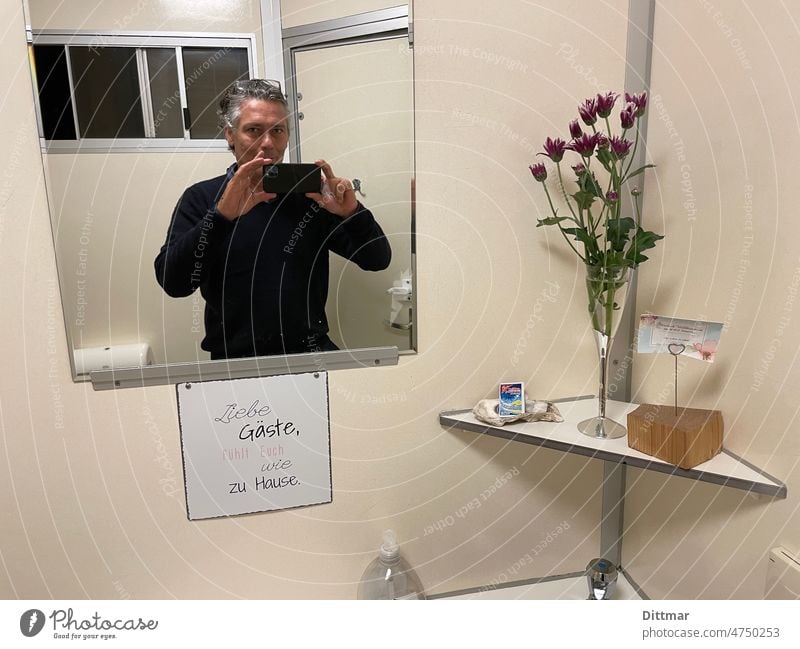 Mann macht Selfie in einer liebevoll gestalteten Campingplatztoilette Spiegel Gastfreundschaft Toilette