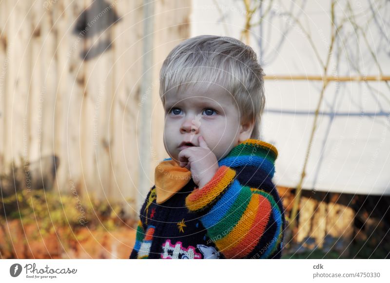 Kindheit | Kleinkind in Regenbogenjacke: für eine friedliche, bunte Welt! Junge blond ernst traurig ruhig still in sich gekehrt Augen Ausdruck Gefühl Hand