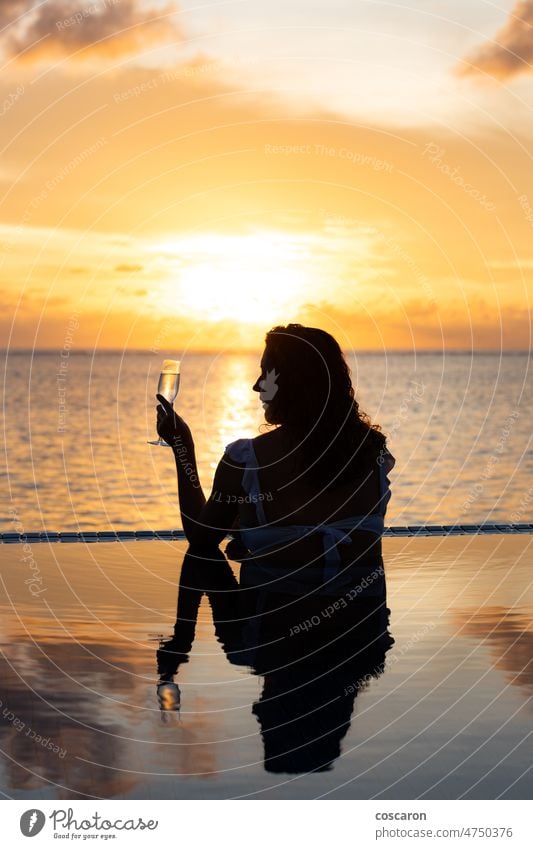 Attraktive Frau an einem Infinity-Pool in der Nähe des Ozeans mit einem Glas Champagner - Blick zurück allein Rücken schön Schönheit Cocktail genießend Abend