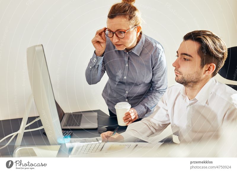 Zwei Geschäftsleute diskutieren über Finanzdaten und schauen auf den Computerbildschirm. Geschäftsfrau im Gespräch mit jungen männlichen Mitarbeiter im Büro. Menschen Unternehmer im Gespräch arbeiten zusammen