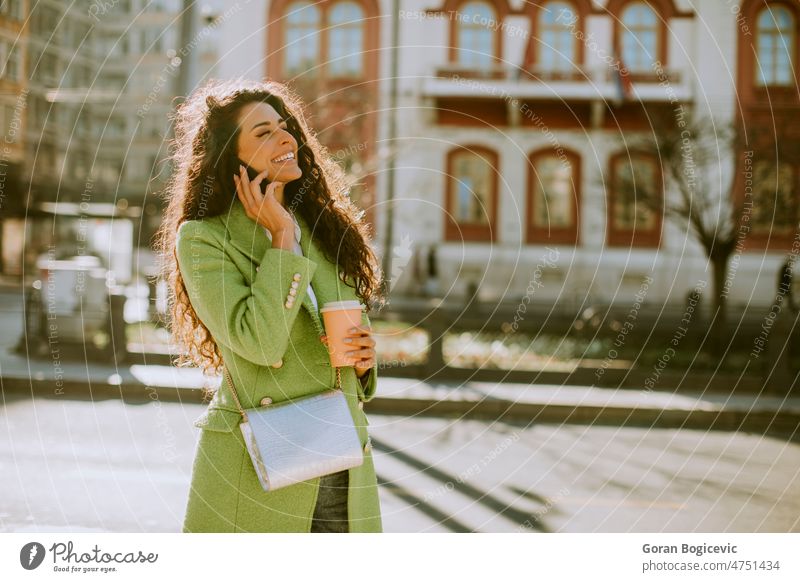 Junge Frau mit Smartphone auf der Straße und Kaffee zum Mitnehmen in der Hand schöne Menschen schöne Frau lässig Funktelefon heiter Großstadt Stadtleben