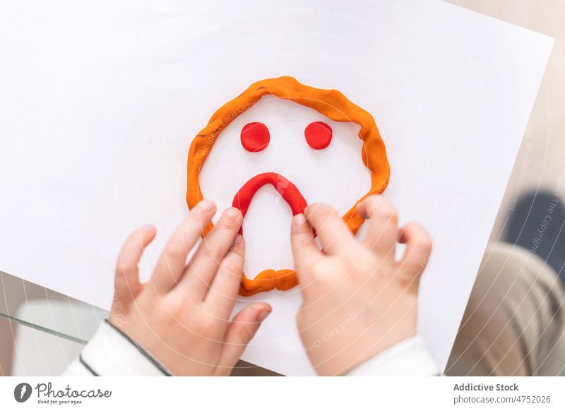 Anonymes Kind, das auf ein trauriges Gesicht zeigt Knetgummi Diagnostik Kindheit besuchen wählen Stimmung Raum Ernennung mental Licht Sitzung Papier geduldig
