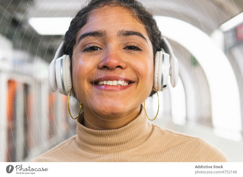 Glückliche ethnische Dame mit Kopfhörern, die wegschaut Frau zuhören benutzend starren Musik Hobby Drahtlos Sorge modern Aufmerksamkeit achtsam Gerät Apparatur