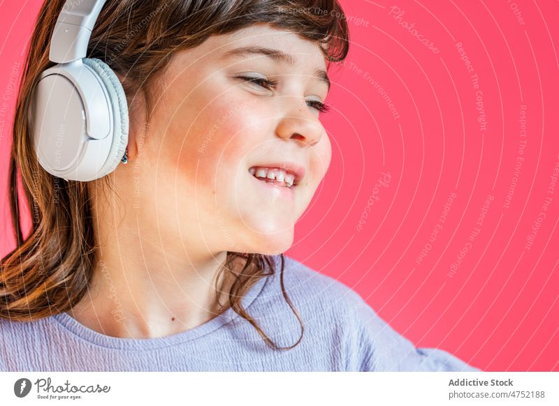 Fröhliches Mädchen hört mit Kopfhörern im Studio Musik Lachen Spaß zuhören hell Freude unterhalten Glück spielerisch genießen Kind Apparatur Vergnügen expressiv