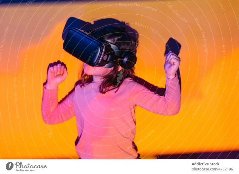 Kleiner Gamer feiert den Sieg im VR-Spiel Mädchen Spieler feiern Erfolg die Faust ballen Erfahrung neonfarbig leuchten Kind Videospiel Gewinner digital