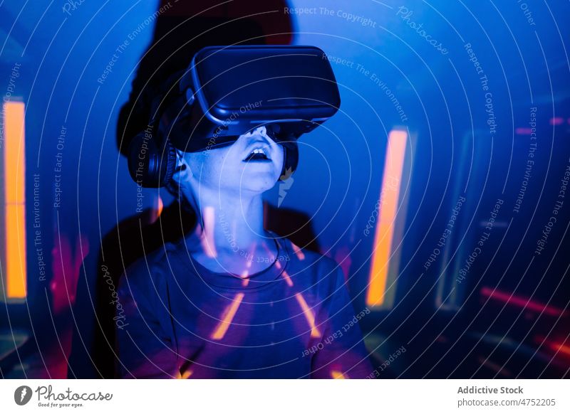 Kleiner Gamer mit VR-Brille Junge Spieler fettarm Wand zuschauen Videospiel erkunden Rotlicht neonfarbig leuchten Farbe Kind Monochrom hell Headset unterhalten