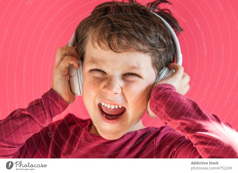 Junge hört mit kabellosen Kopfhörern im Studio Lieder zuhören Lächeln benutzend Wiedergabeliste Drahtlos Musik Freizeit Apparatur Gesang Kind heiter aufgeregt
