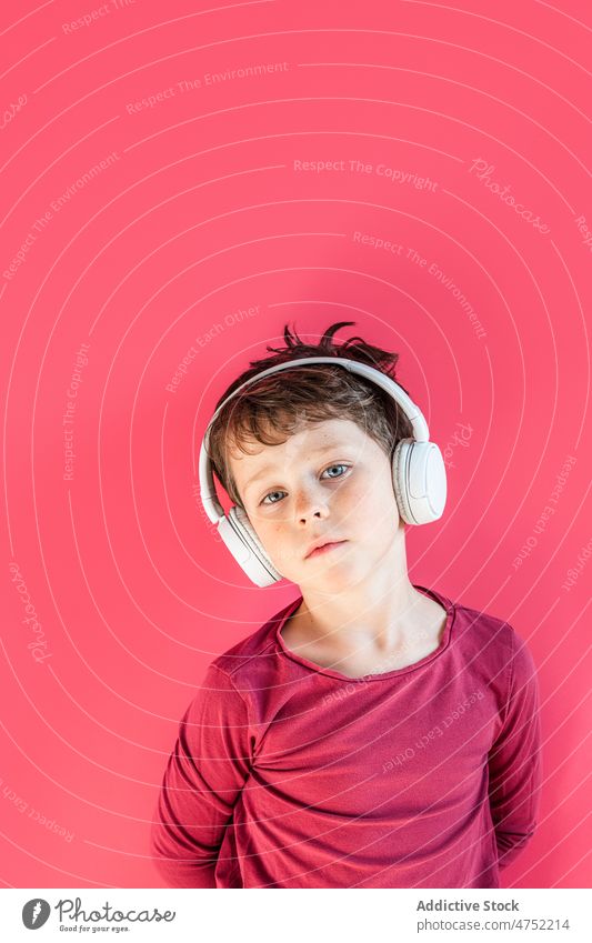 Junge hört mit kabellosen Kopfhörern im Studio Lieder zuhören benutzend Wiedergabeliste Drahtlos Musik Freizeit Apparatur Gesang Lächeln Kind lebhaft sorgenfrei