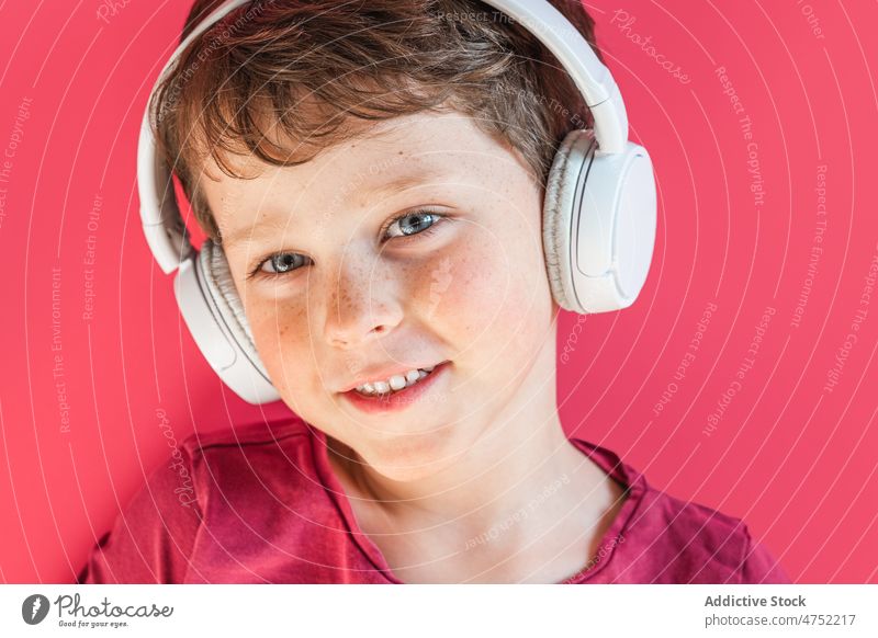 Junge hört mit kabellosen Kopfhörern im Studio Lieder zuhören Lächeln benutzend Wiedergabeliste Drahtlos Musik Freizeit Apparatur Gesang Kind heiter lebhaft
