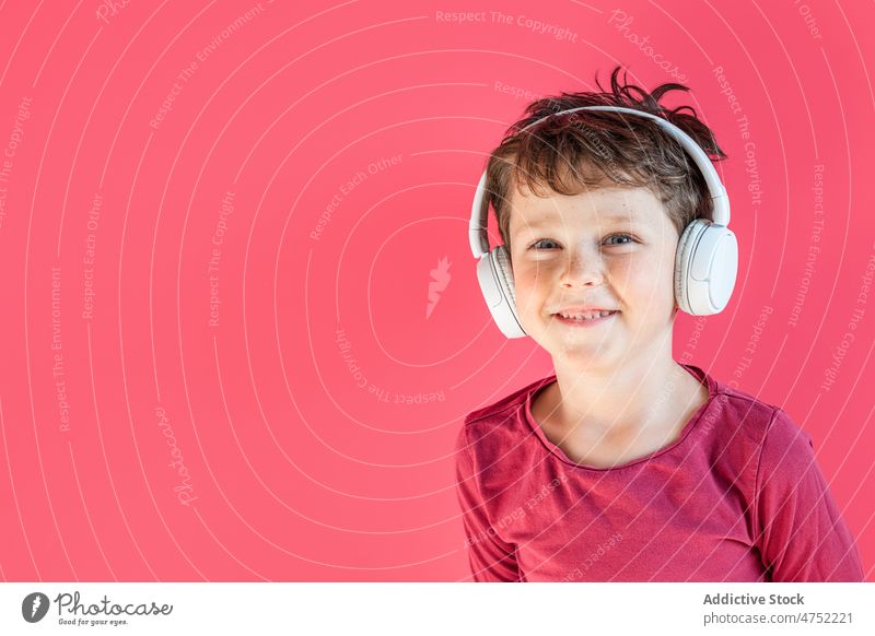 Junge hört mit kabellosen Kopfhörern im Studio Lieder zuhören Lächeln benutzend Wiedergabeliste Drahtlos Musik Freizeit Apparatur Gesang Kind heiter lebhaft