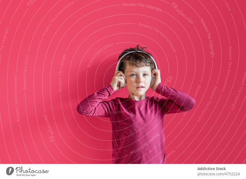 Junge hört mit kabellosen Kopfhörern im Studio Lieder zuhören benutzend Wiedergabeliste Drahtlos Musik Freizeit Apparatur Gesang Lächeln Kind lebhaft sorgenfrei
