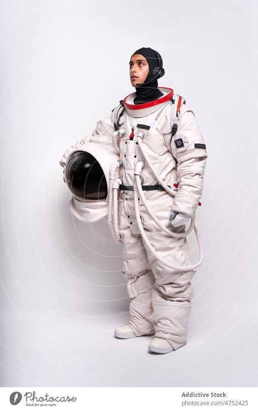 Seriöser ethnischer Astronaut in Raumanzug und Headset im Studio Mann Schutzhelm Sicherheit Astronomie Missionsstation Vorschein Schmuckkörbchen männlich
