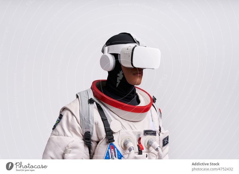 Ethnischer Astronaut in Raumanzug und VR-Brille im Studio Mann Metaversum Schmuckkörbchen Schutzbrille interagieren erkunden Virtuelle Realität Porträt