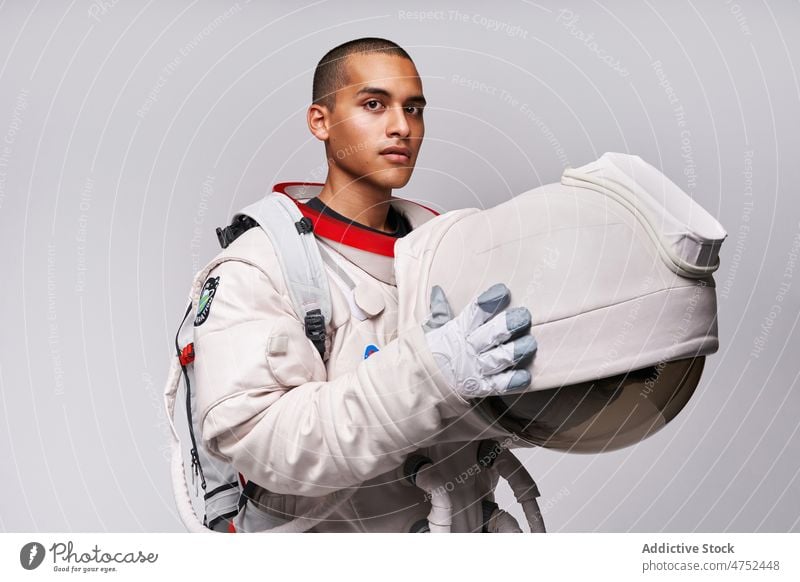 Astronaut nimmt im Studio den Helm des Raumanzugs ab Kosmonaut Fundstück Mut Konzept Model Studioaufnahme erkunden Weltall Panzerung Abheben Flug Uniform Latein