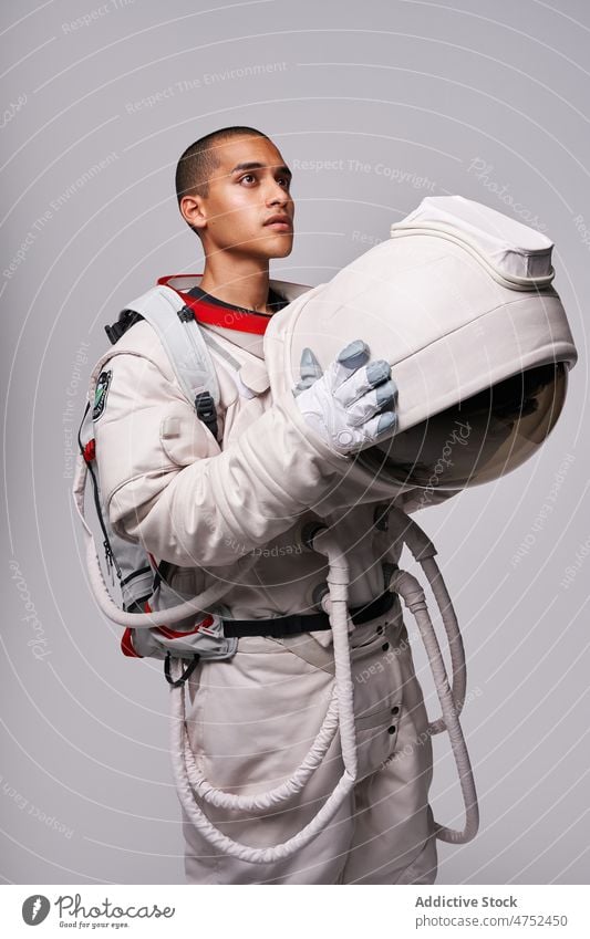 Astronaut nimmt im Studio den Helm des Raumanzugs ab Kosmonaut Fundstück Mut Wegsehen Konzept Model Studioaufnahme erkunden Weltall Panzerung Abheben Flug