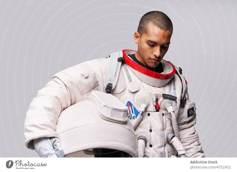 Astronaut nimmt im Studio den Helm des Raumanzugs ab Kosmonaut Fundstück Mut Wegsehen Konzept Model Studioaufnahme erkunden Weltall Panzerung Abheben Flug