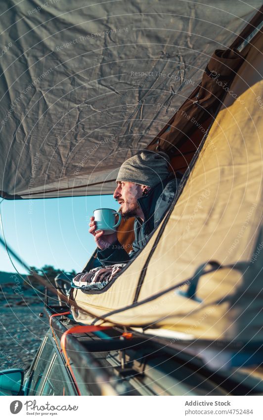 Mann trinkt heißes Getränk im Campingzelt bei Sonnenaufgang Wohnmobil Zelt Morgen Kaffee bewundern sich[Akk] entspannen Erholung Freiheit männlich Reisender