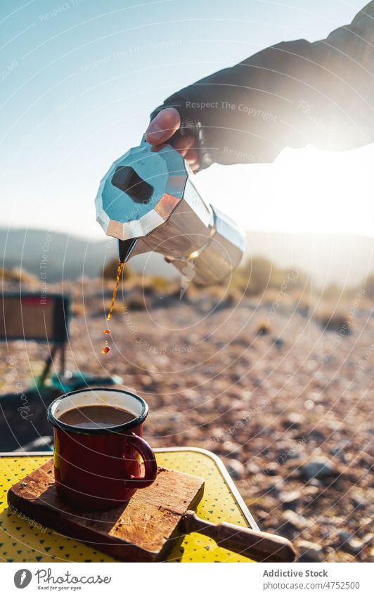 Person gießt auf einem Campingplatz aromatischen Kaffee aus einer Moka-Kanne ein Wanderer eingießen Moka-Topf heiß Wanderung Frühstück brauen Morgen erkunden