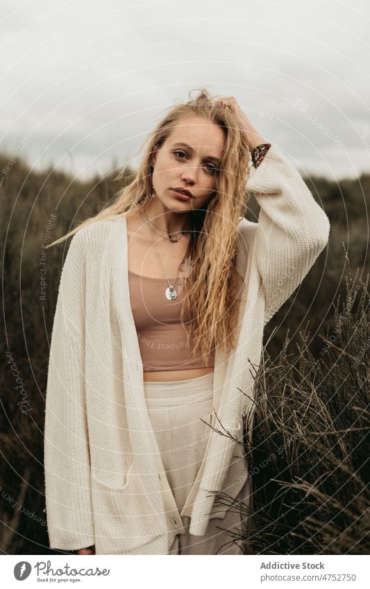Frau steht auf einem grasbewachsenen Feld auf dem Lande Landschaft Porträt Natur Vorschein feminin Stil attraktiv jung ländlich blond Haare berühren Umwelt