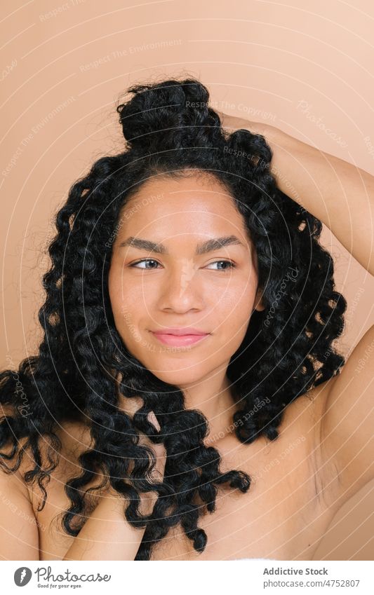 Lächelnde schwarze Frau, die ihr Haar berührt Haare berühren Spaß haben Vorschein Frisur feminin kräuseln Porträt Stil trendy Glück Atelier attraktiv charmant