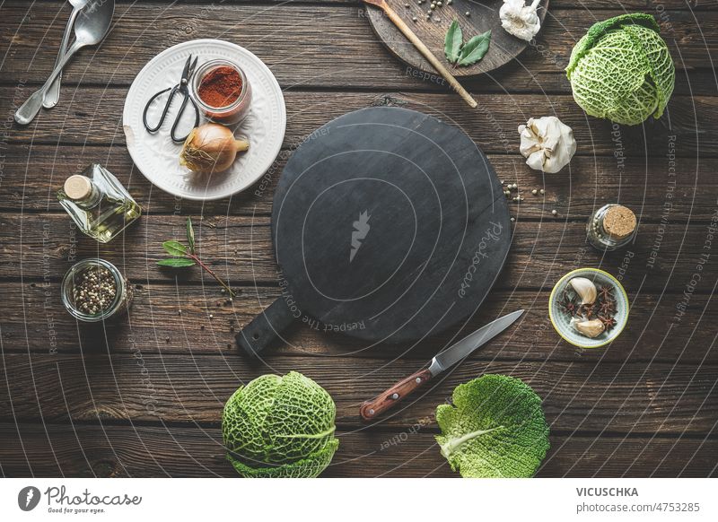 Lebensmittel Hintergrund mit leeren runden Schneidebrett, ganze Wirsing und Küchenutensilien Lebensmittelhintergrund Gewürze rustikal hölzern Tisch