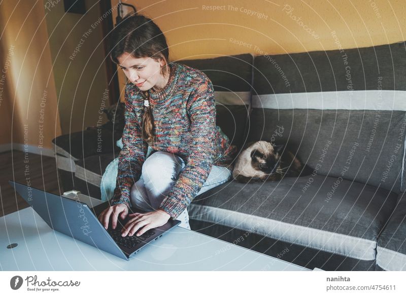 Junge Frau bei Telearbeit zu Hause in der Nähe ihres Haustiers Single Katze soziale Netzwerke aussruhen heimwärts siamesisch Liebe Familie Routine