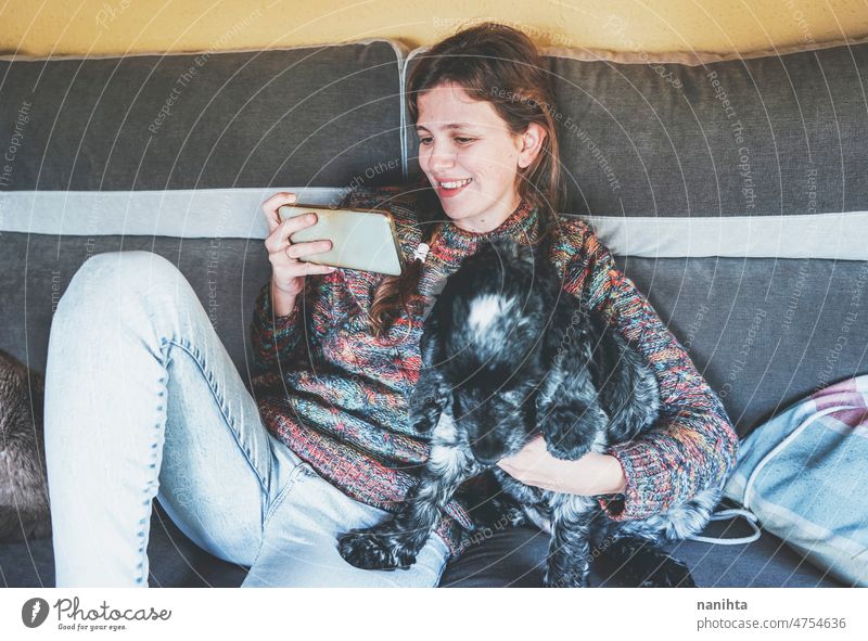 YOung Frau mit ihrem Smartphone weißen Stand mit ihrem Hund Single Telefon heimwärts Familie aussruhen Sofa Mobile Fröhlichkeit Glück Windstille ruhig Szene