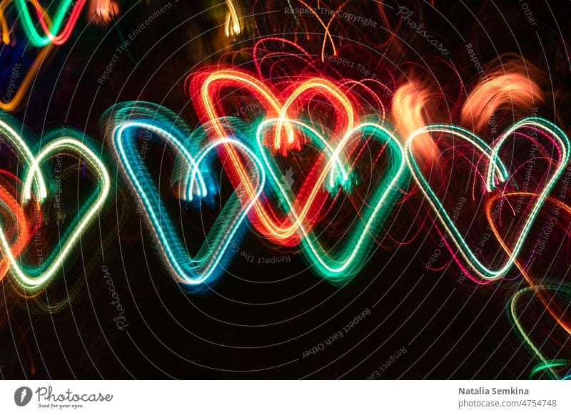 Reihe von bunten, neonleuchtenden Herzen auf schwarzem Hintergrund. neonfarbig Langzeitbelichtung glühend Laser abstrakt Kunst hell Farbe orange Party Muster
