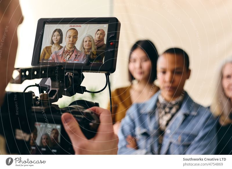 Videofilmerin filmt eine Gruppe multiethnischer Frauen zum Internationalen Frauentag mit digitalem Bild auf dem Kamerabildschirm hinter den Kulissen BTS am Set