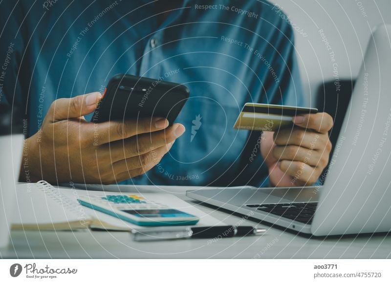 Mann Hand hält Kreditkarte und Mobiltelefon Online-Shopping E-Commerce und Internet-Banking am Schreibtisch. Finanzen kaufen online Mobile Business Telefon