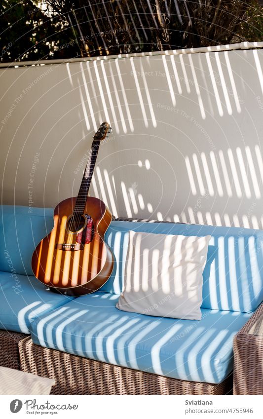 Eine akustische Gitarre steht auf einem blauen Sofa neben einem Kissen auf der Terrasse Stil Raum Design Innenbereich Hintergrund Appartement Holz Kopie Textil