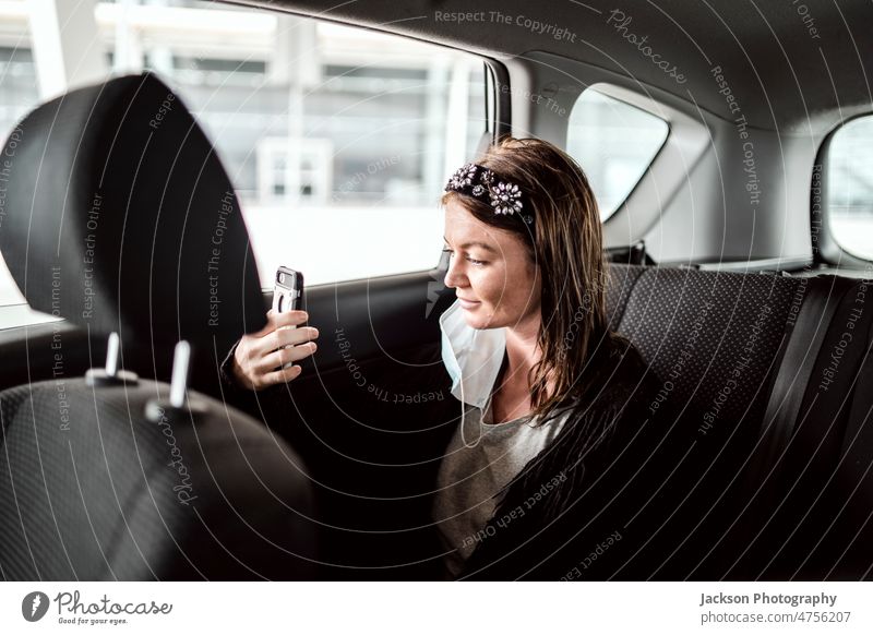Ein Taxi- oder Uber-Fahrgast, der auf dem Rücksitz in sein Telefon spricht PKW Frau uber sprechen reden zeigend Flughafen Rücken Lächeln Person Business Pendler