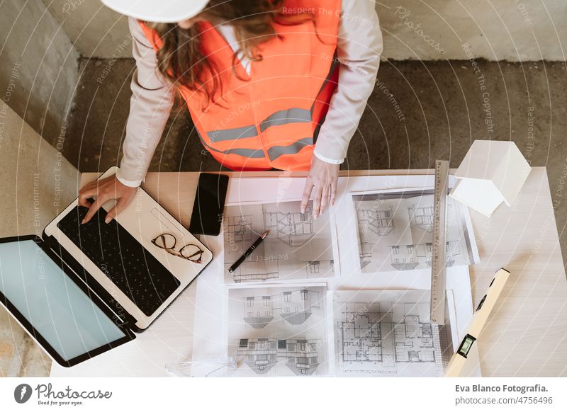 Draufsicht auf eine professionelle Architektin auf einer Baustelle, die an einem Laptop und Plänen arbeitet unkenntlich Handy Blaupausen Frau Arbeitsbereich