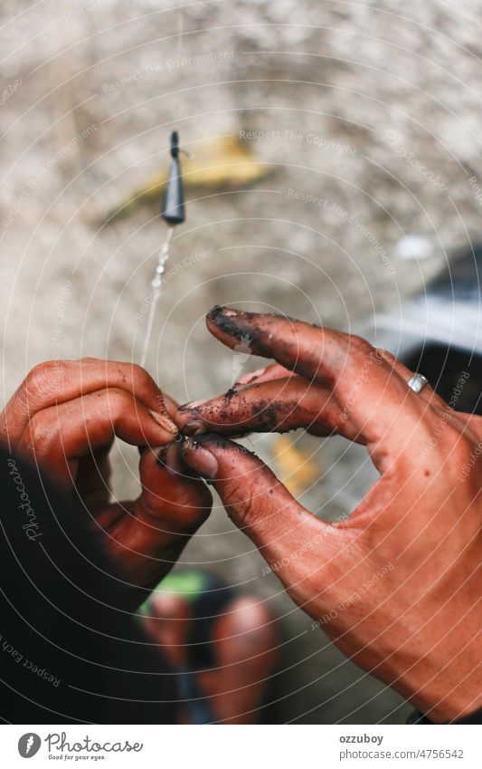 Close up schmutzige Hand setzen Köder Wurm auf den Haken. Fischer für die Fischerei vorbereitet Fischen Tier Regenwurm fangen vereinzelt ködern Natur Angelhaken
