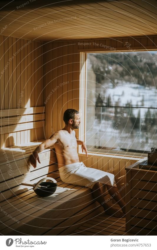Junger Mann entspannt sich in der Sauna und beobachtet den Winterwald durch das Fenster Kaukasier Körper Erholung Bad Finnland sich[Akk] entspannen Therapie