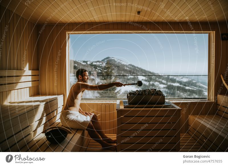 Junger Mann gießt Wasser auf einen heißen Stein in der Sauna Aktivität Erwachsener Bad Badehaus Vollbart bärtig Schönheit Bank Körper Kaukasier bequem Genuss