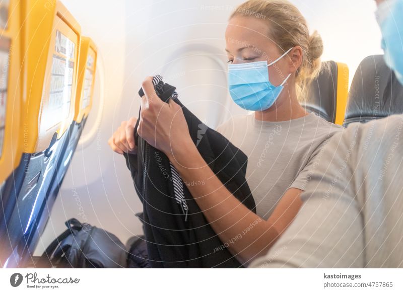 Eine junge Frau trägt eine Gesichtsmaske, während sie im Flugzeug reist. Neue Normalität des Reisens nach dem Konzept der Covid-19-Pandemie reisen Reisender