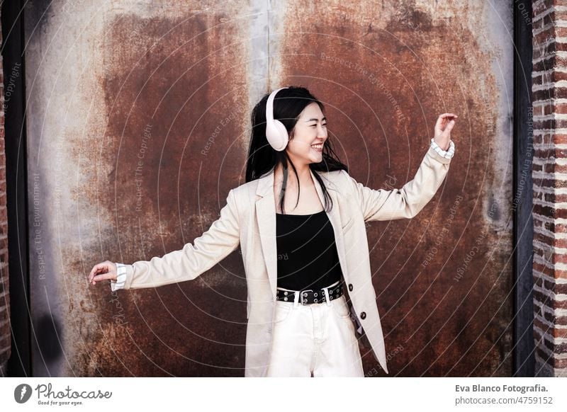glückliche Geschäftsfrau, die mit Kopfhörern und Mobiltelefon Musik hört und in der Stadt unbeschwert tanzt Glück Tanzen Chinesisch Frau Großstadt Handy Lächeln